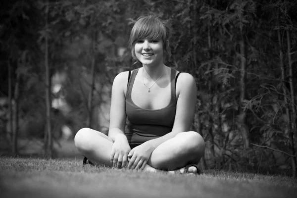 Foto de mulher sentada de pernas cruzadas na grama no parque — Fotografia de Stock