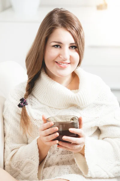 Portrait de femme souriante assise sur un canapé et tenant une tasse de thé — Photo