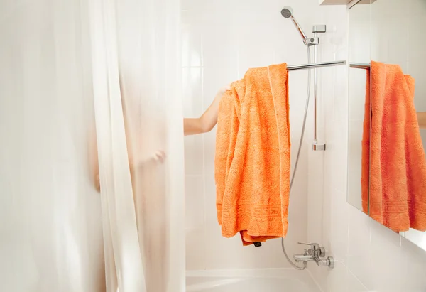 Mujer en la ducha quitando toalla naranja del gancho —  Fotos de Stock