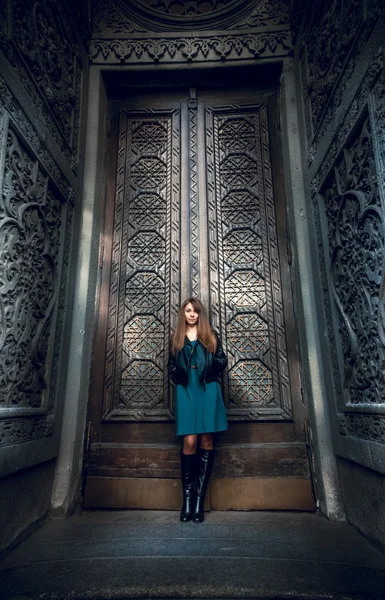 Donna alla moda appoggiata alle alte porte filettate — Foto Stock
