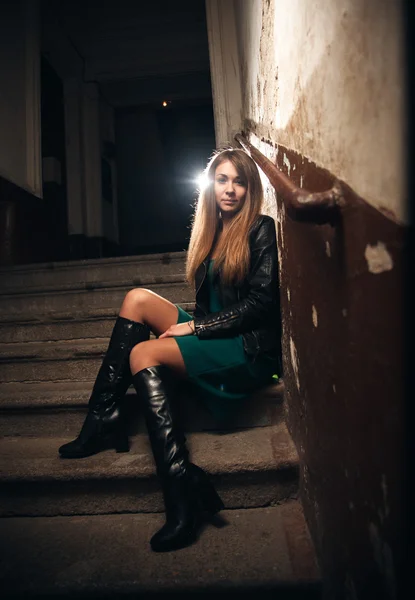 Hermosa chica sentada en la escalera en el edificio viejo — Foto de Stock