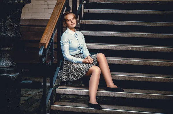 Portret van een jonge vrouw in shirt en rok zittend op oude trap — Stockfoto