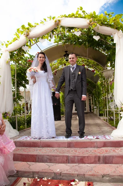 Pareja casada cogida de la mano mientras está de pie en las escaleras en el parque — Foto de Stock