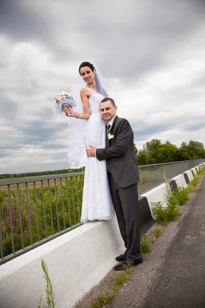 Newly married couple standing on road — Stock Photo, Image