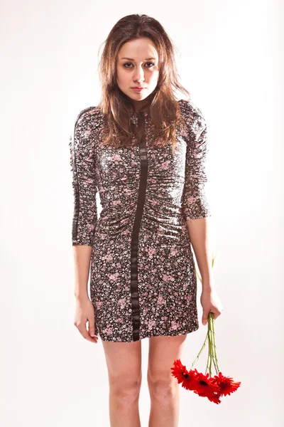 Woman in dress posing holding red flowers — Stock Photo, Image