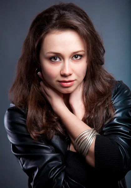 Portrait of sexy brunette in leather coat holding hands on neck Stock Picture