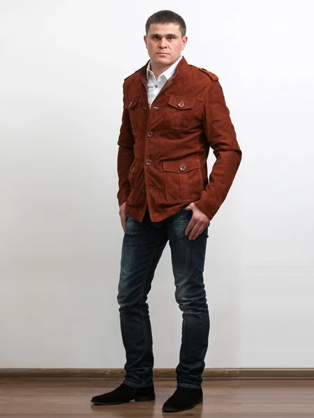 Человек в джинсах и красной замшевой куртке на белом фоне — стоковое фото