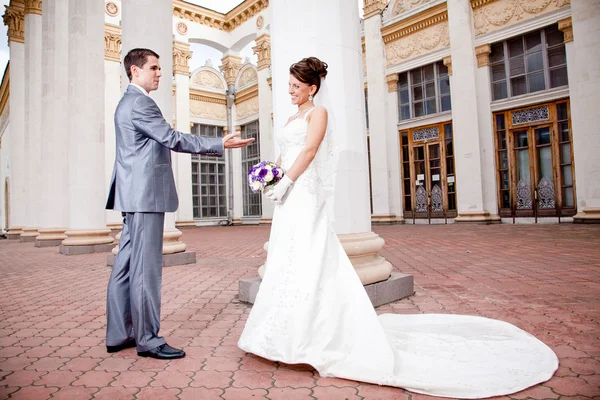 Жених протягивает руку красивой невесте в платье с длинной петлей — стоковое фото