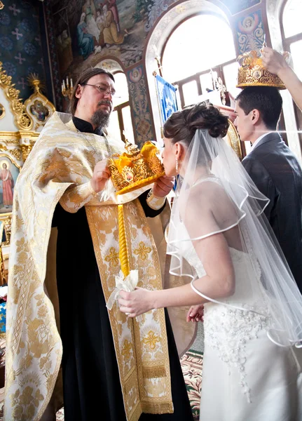 Bruid kussen gouden kroon op orthodoxe huwelijksceremonie — Stockfoto