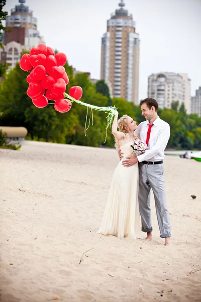 Bruid houden bos van rode ballonnen op strand — Stockfoto