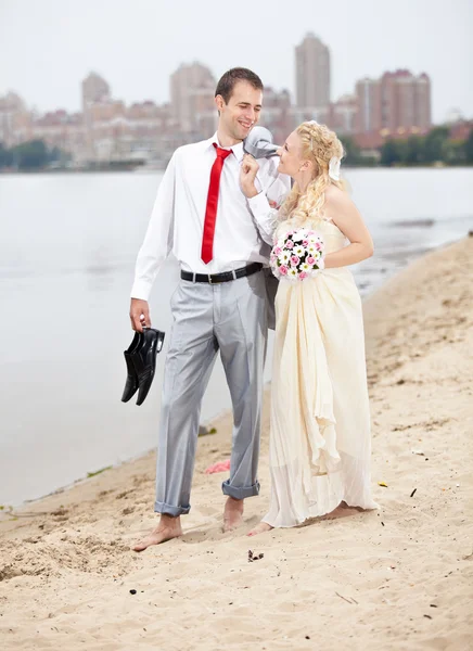 Bride and groom walking on beach and talking — Stock Photo, Image