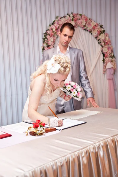 Blonde bruid ondertekening bruiloft contract bij bruiloft kantoor — Stockfoto