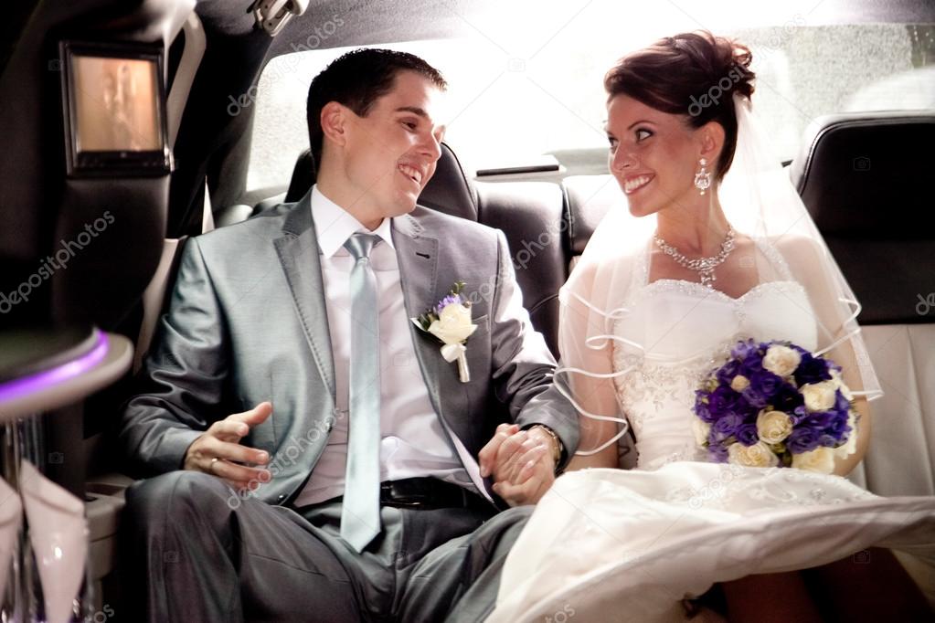 Bride and groom looking at each other on backseat of car
