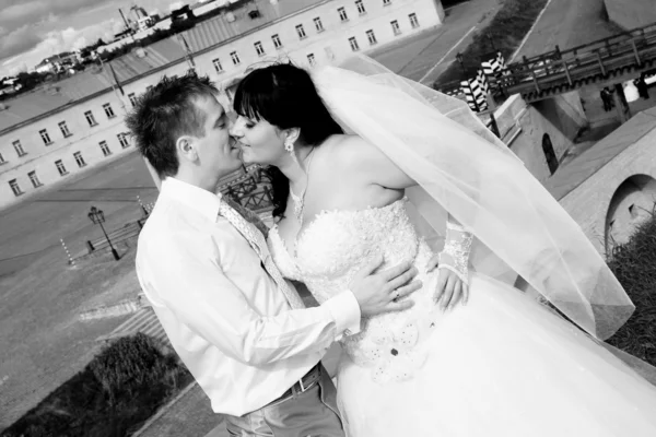 Portrait of bride and groom kissing on hill against old fort — Stock Photo, Image