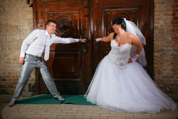 Married couple opening old wooden doors — Stock Photo, Image