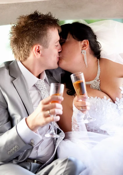 Portrait of bride and groom kissing on back seat at car — Stock Photo, Image