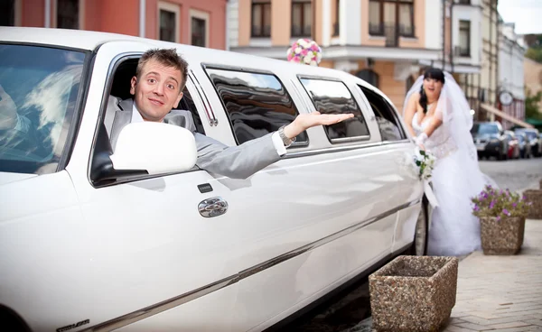 Groom sitting in car while bride pushing it — Stock Photo, Image