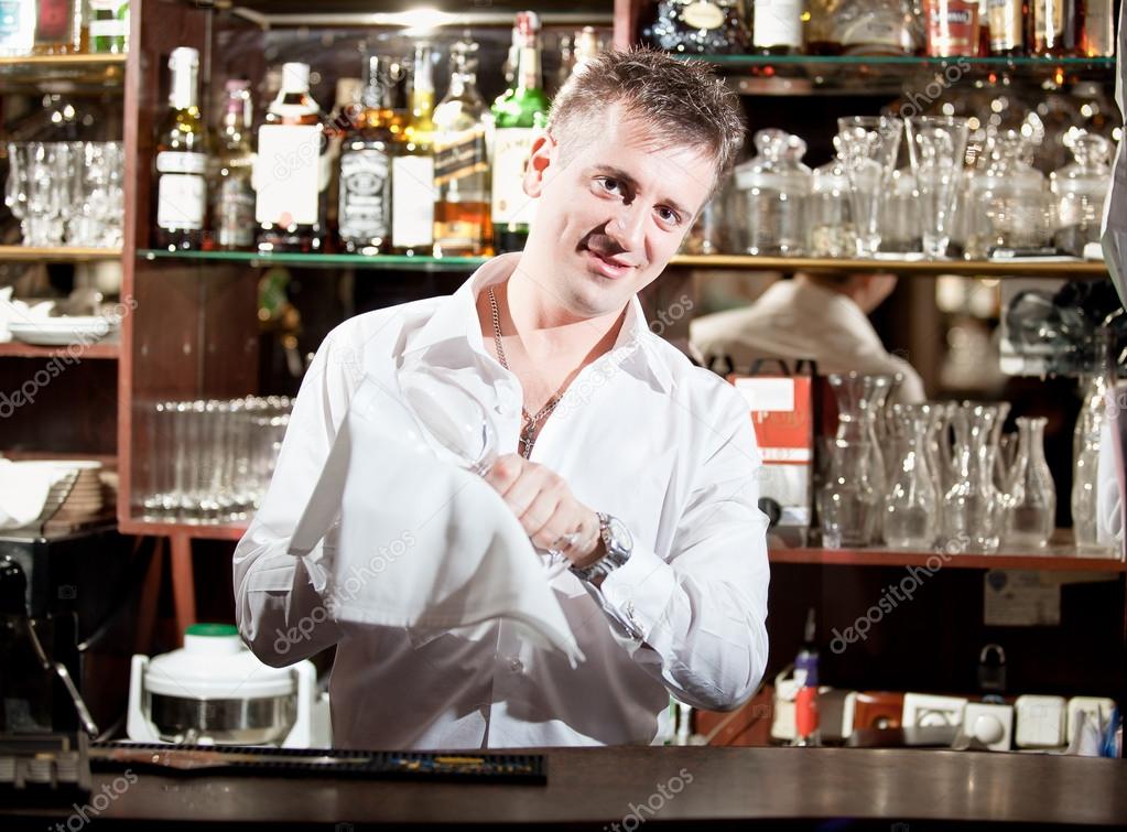 Barman cleaning glasses with white cloth