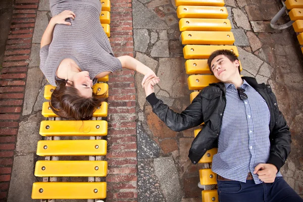 热恋中的爱在两个板凳上，手牵着手的情侣 — 图库照片