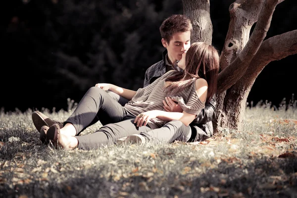 Foto van paar in liefde liegen en kussen onder boom — Stockfoto