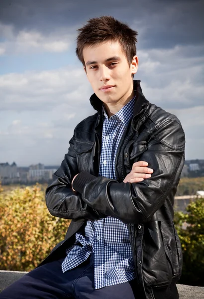 Handsome guy in black coat posing against beautiful landscape — Stock Photo, Image