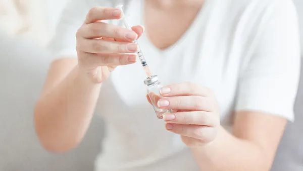 Shot of young woman in white filling syringe with liquid — Stock Photo, Image