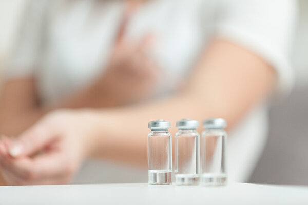 Photo of woman doing injection behind empty ampules