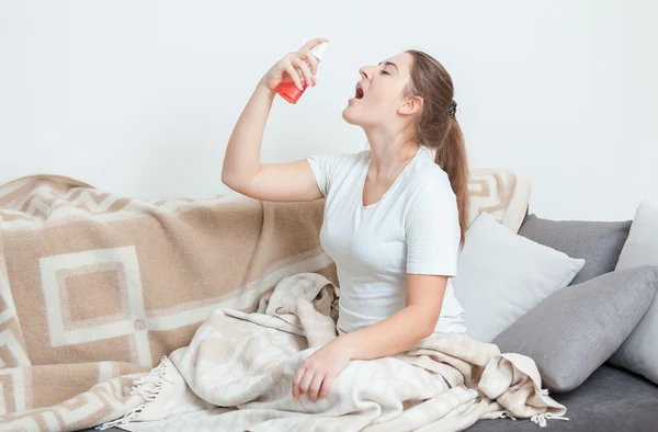 Mujer enferma acostada en la cama y usando aerosol para la garganta — Foto de Stock