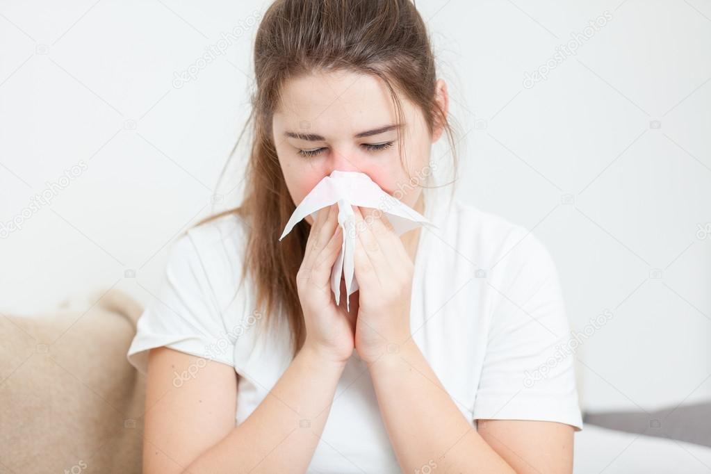 Ortrait of brunette woman sneezing in paper tissue