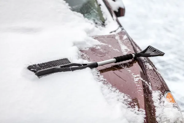 Spazzola nera sdraiata sulla macchina coperta di neve — Foto Stock