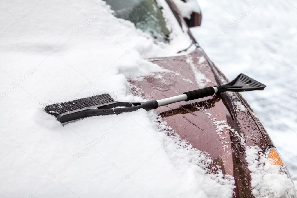 Black brush lying on car covered in snow