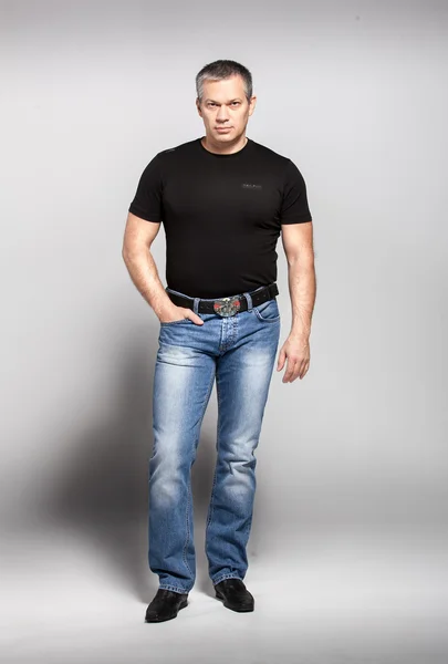 Uomo adulto in t-shirt nera e jeans in posa in studio — Foto Stock