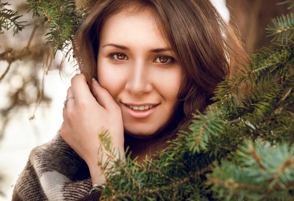 Portrait of young woman in plaid behind fir tree — Stock Photo, Image