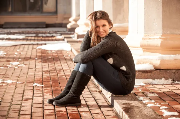 Young romantic woman in black sweater sitting on street — Stock Photo, Image
