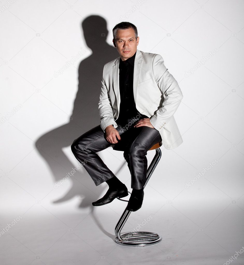 Man in suit sitting on bar chair against white background