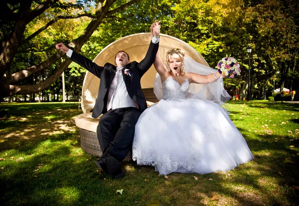 Newly married couple jumping on couch at park — Stock Photo, Image