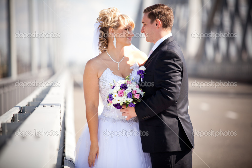 Newly married couple looking at each other on bridge