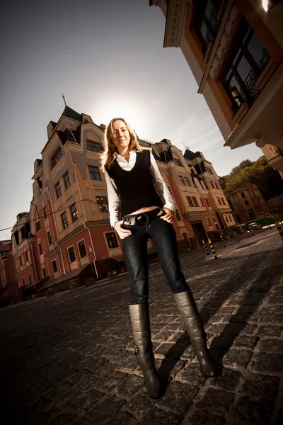 Blonde woman with long legs standing on street against old building — Stock Photo, Image