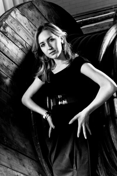 Ritratto di donna carina in abito nero appoggiato alla grande bobina — Foto Stock
