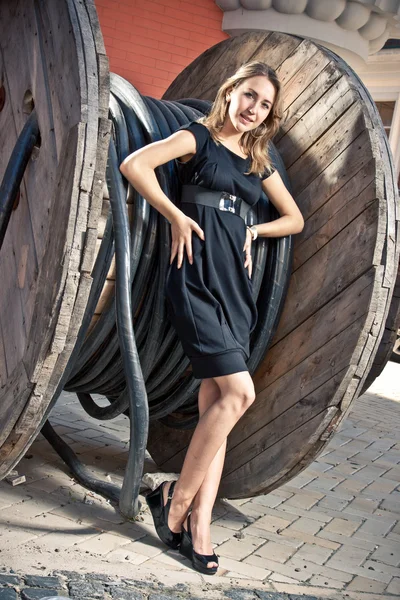 Photo of beautiful blonde woman leaning against industrial bobbin — Stock Photo, Image