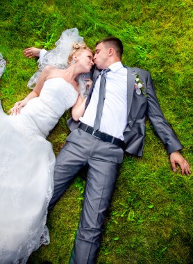 Yeni evli çift çim üzerinde yalan ve öpüşme