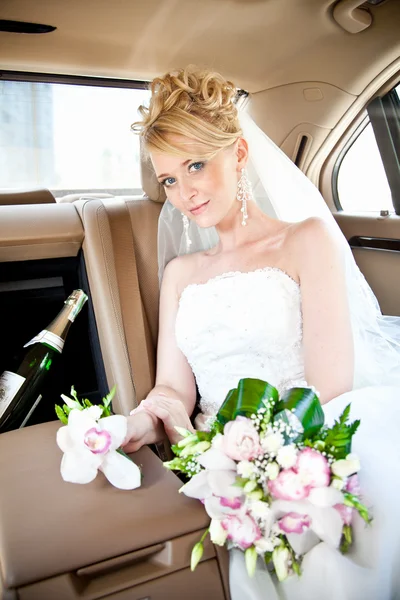 Belle mariée blonde assise sur le siège arrière d'une voiture de luxe — Photo