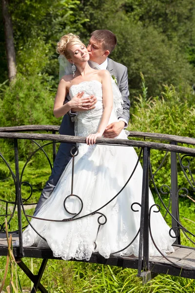 Sposo abbracciare sposa da indietro sul ponte vintage — Foto Stock