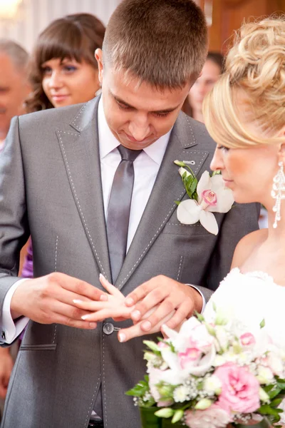 Jovem noivo bonito colocando anel de casamento em noivas dedo — Fotografia de Stock