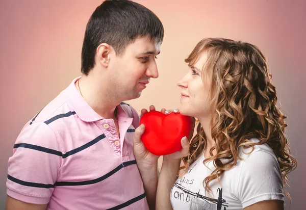 Hombre y mujer mirándose unos a otros y sosteniendo el corazón rojo entre — Foto de Stock