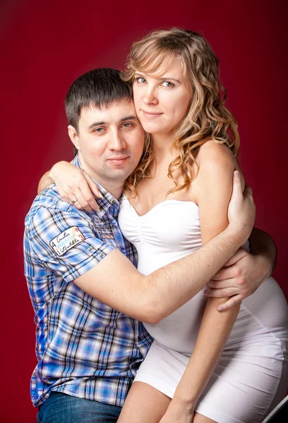 Retrato do marido abraçando a esposa grávida sentada nas pernas — Fotografia de Stock