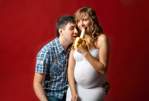 Těhotná žena, sedící vedle manžela jíst banán — Stock fotografie