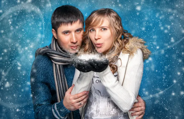 Portrait of young couple blowing snowflakes from hands — Stock Photo, Image