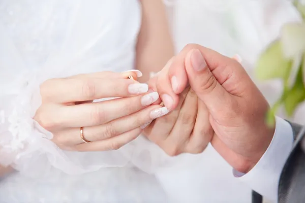 Молодая невеста надевает обручальное кольцо на руки жениха — стоковое фото