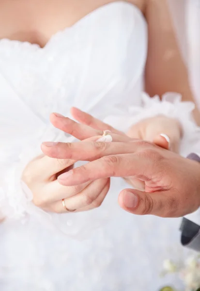 Novia en vestido blanco poniendo anillo de bodas en los novios dedo — Foto de Stock
